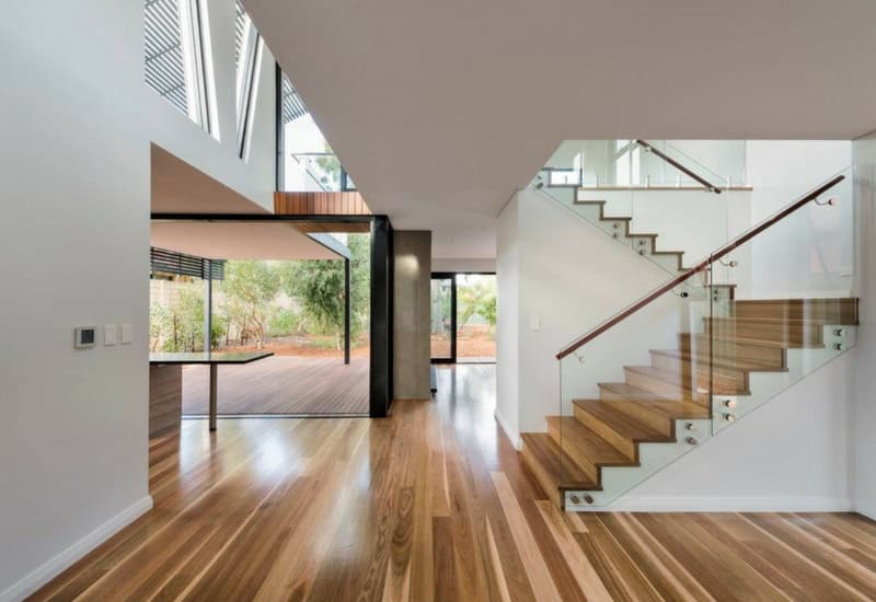 Open plan home interior featuring spotted gum timber floors and a matching timber staircase, styled with natural light and modern furnishings.